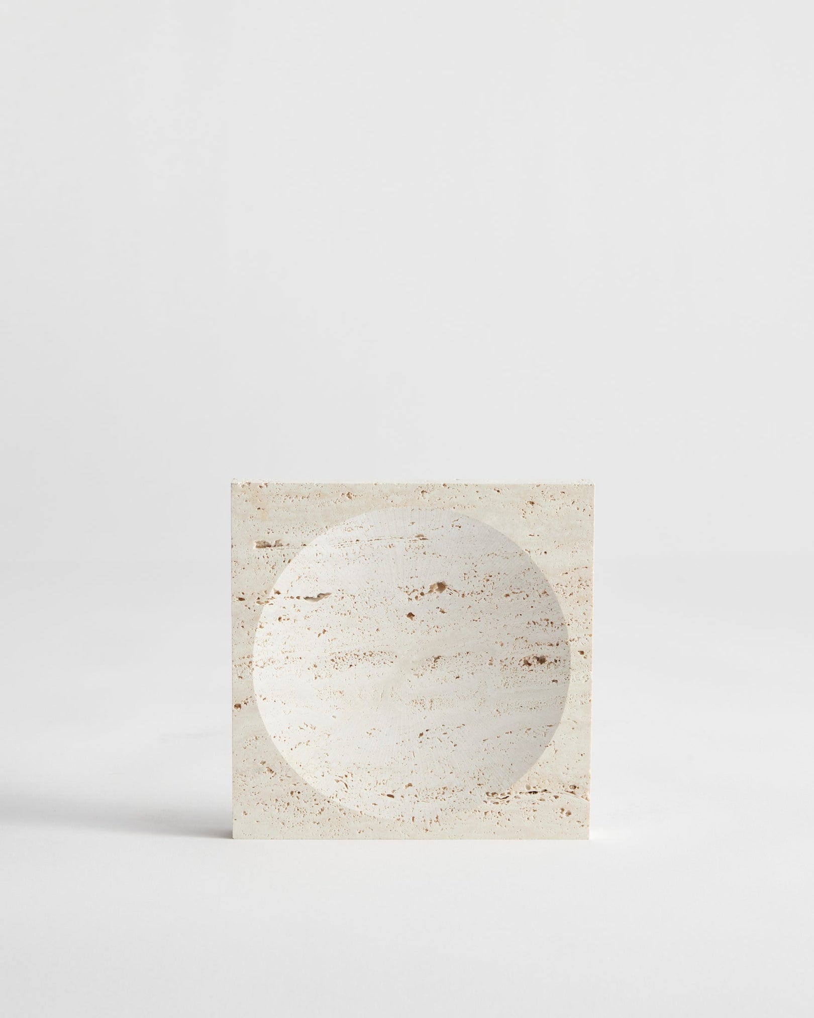 Small tray | travertine: A handcrafted square travertine block with a circular indent, showcasing minimalist design. Made in the Netherlands by artist Louis Crombag.