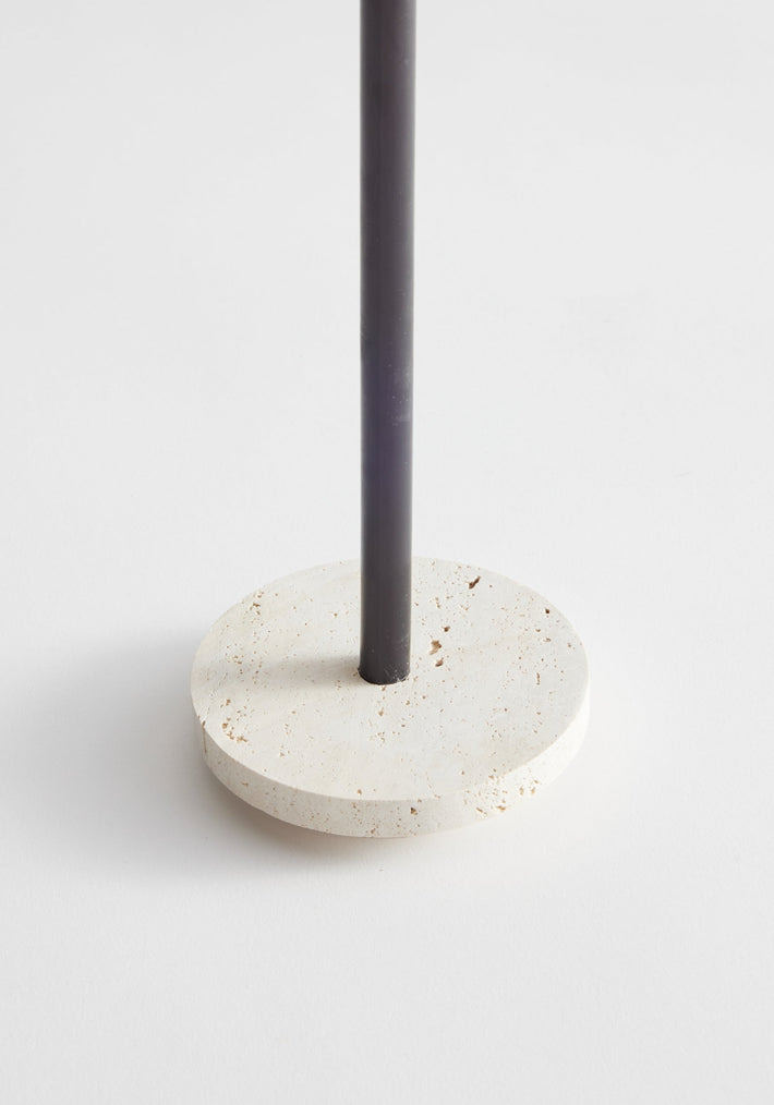 Dish candleholder small | travertine, featuring a circular travertine base with a vertical black metal rod, crafted by Louis Crombag in the Netherlands. Comes with two fitting candles.