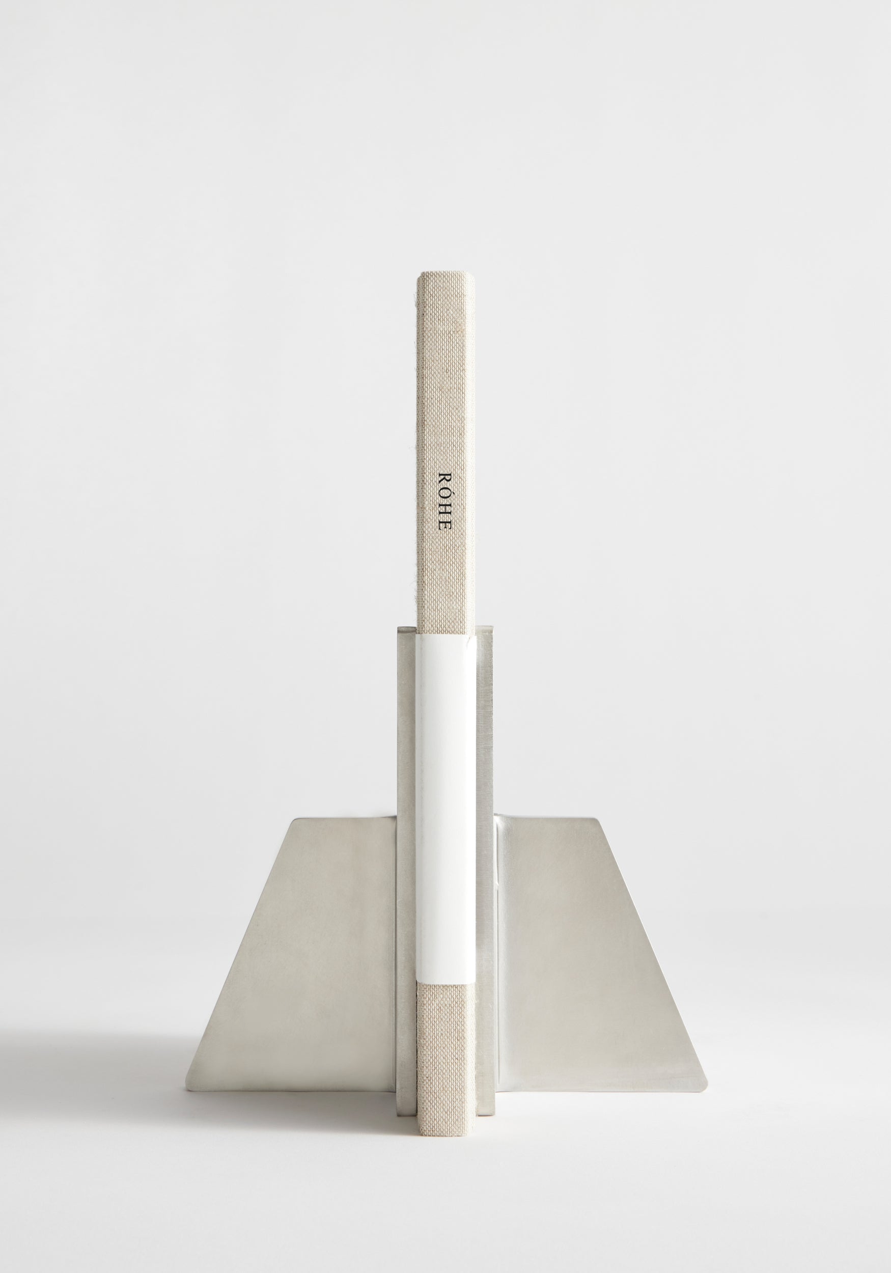 Stainless steel bookends showcasing a single cloth-bound book, ROHE, in an angular, handcrafted design by Paul Coenen, made from 8mm thick stainless steel.
