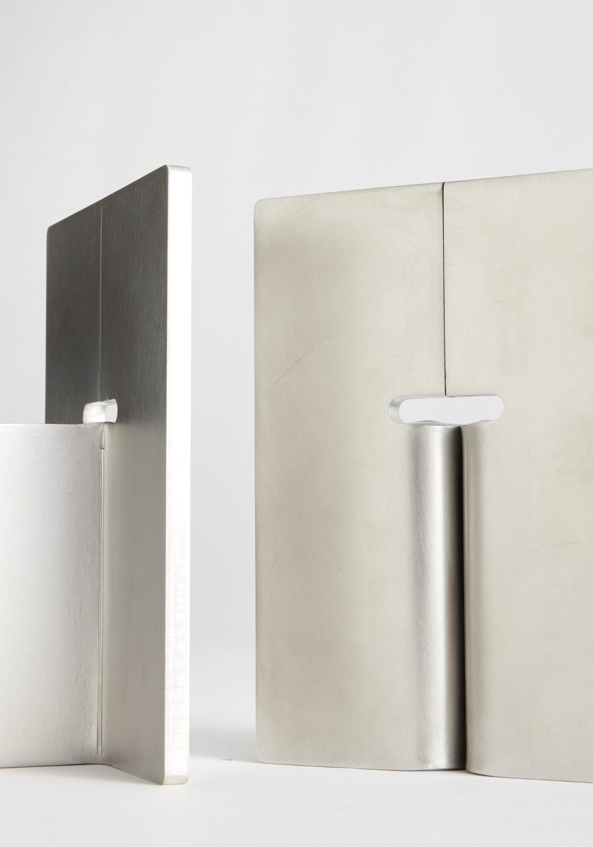 Stainless steel bookends | stainless steel, minimalist brushed metal bookends displayed beside standing books on a white background