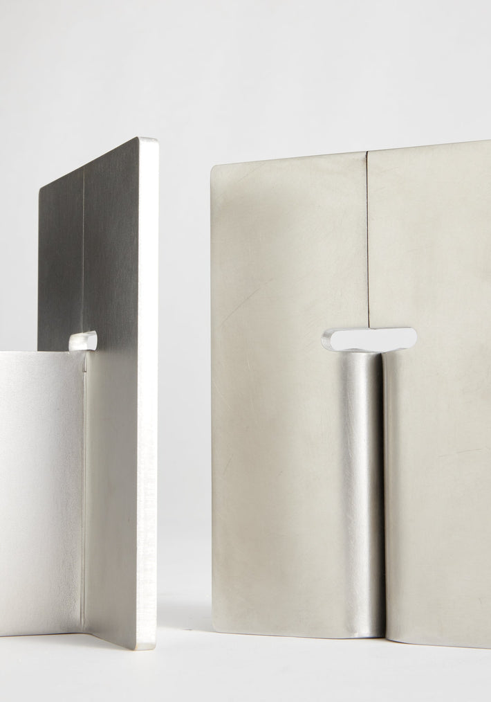 Stainless steel bookends: Two minimalist, handcrafted bookends made of 8mm thick stainless steel, featuring a vertical plate with a base flange and an elongated slot.