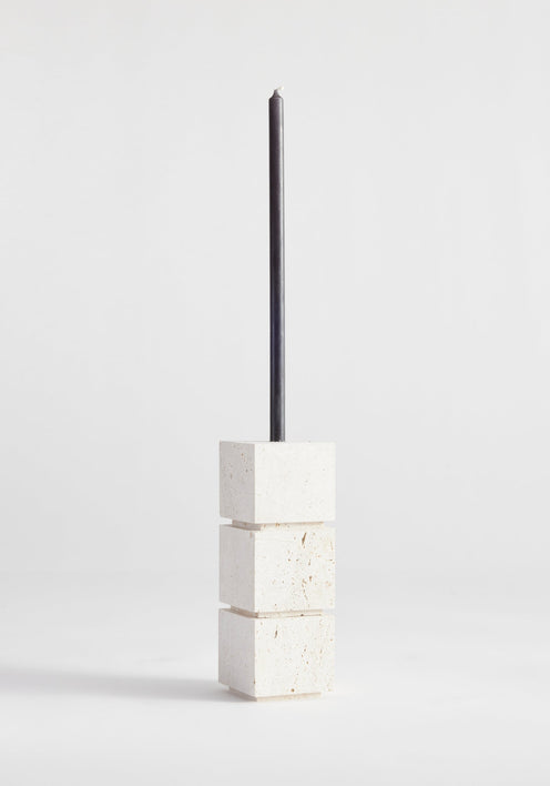 Sculptural candle holder small | travertine: Three stacked stone cubes with a black taper candle, handcrafted from Italian travertine by Dutch artist Louis Crombag.