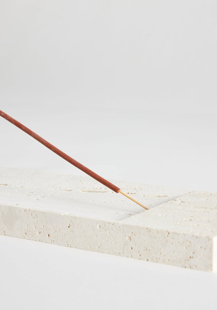 Incense holder tray | travertine: A handcrafted travertine tray by Louis Crombag, featuring an unlit incense stick, showcasing minimalist design and natural uniqueness.