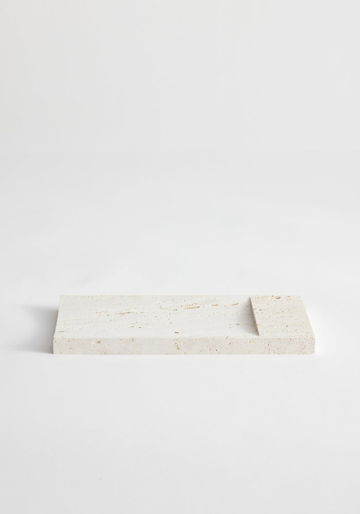 Travertine incense holder tray with a shallow recessed area, handcrafted by Louis Crombag from leftover stone, showcasing a unique speckled pattern.