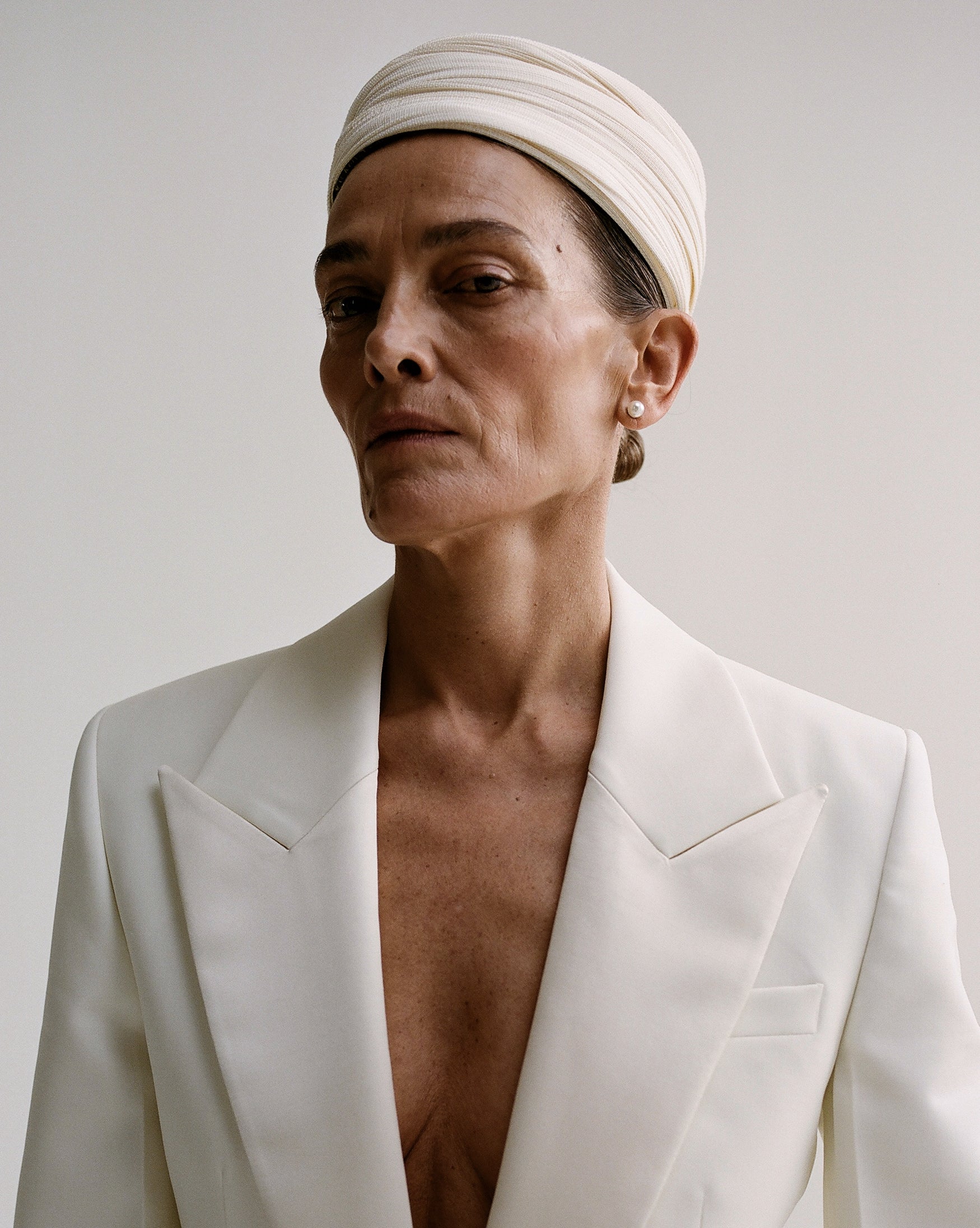 Woman wearing a white blazer and hat. 