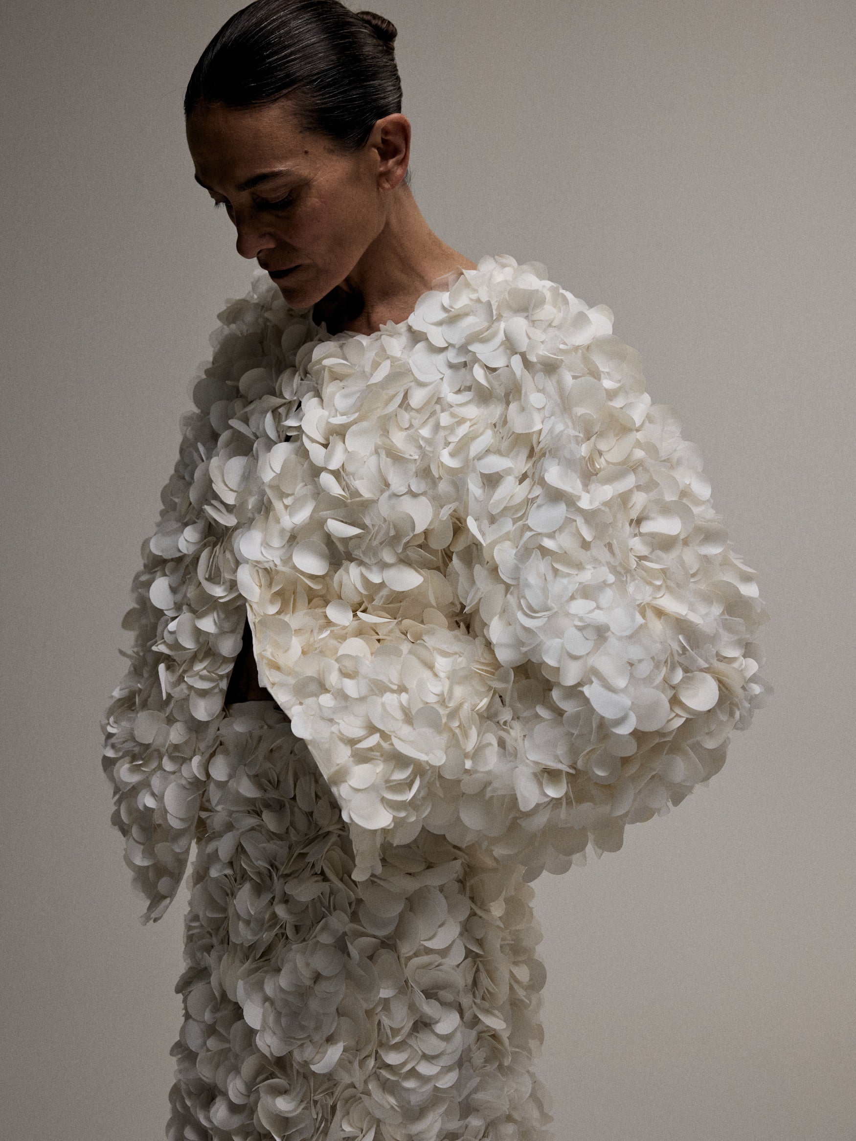 Woman white sequin top and skirt standing against a white backdrop.