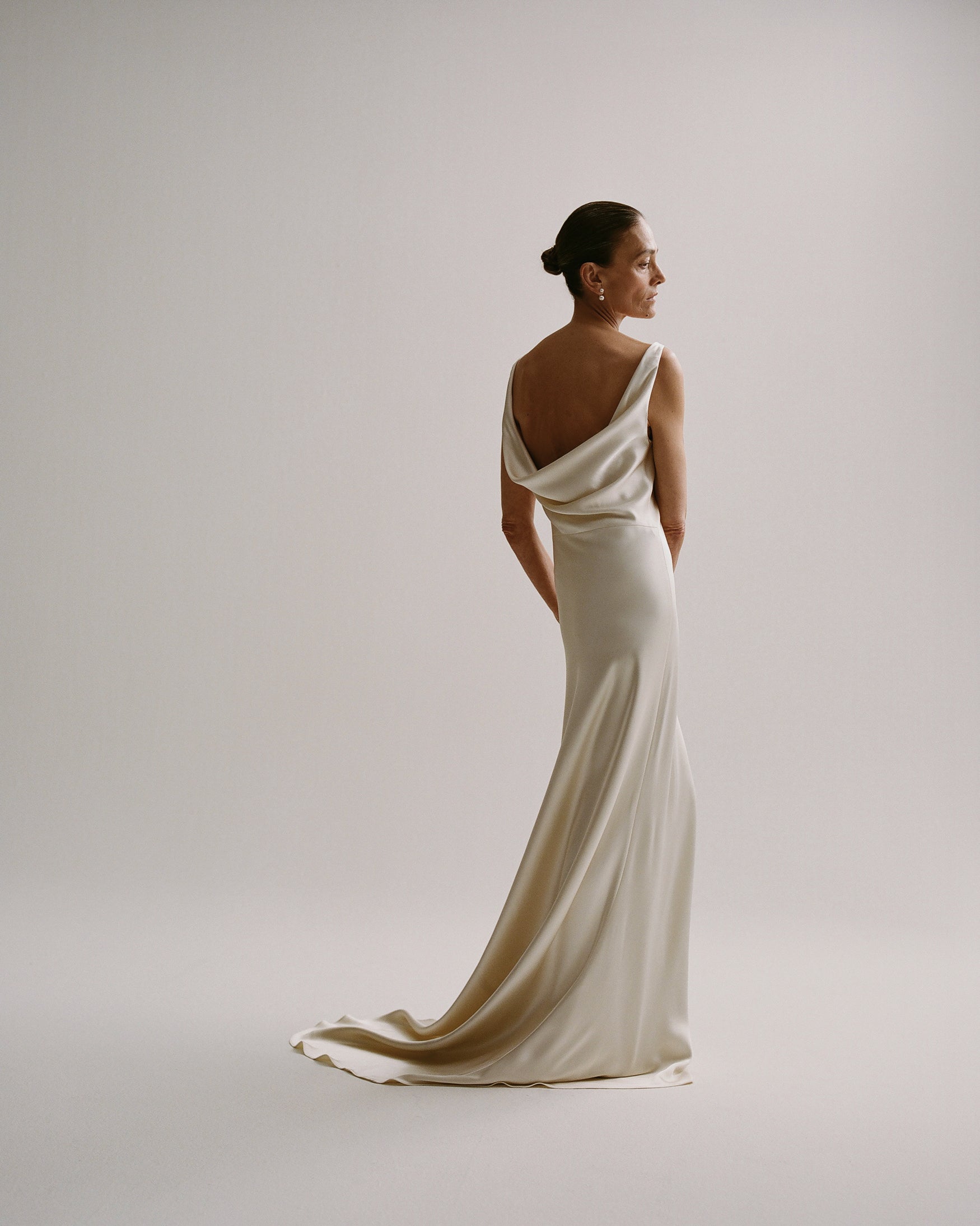 Woman in a satin long dress standing against a white backdrop.
