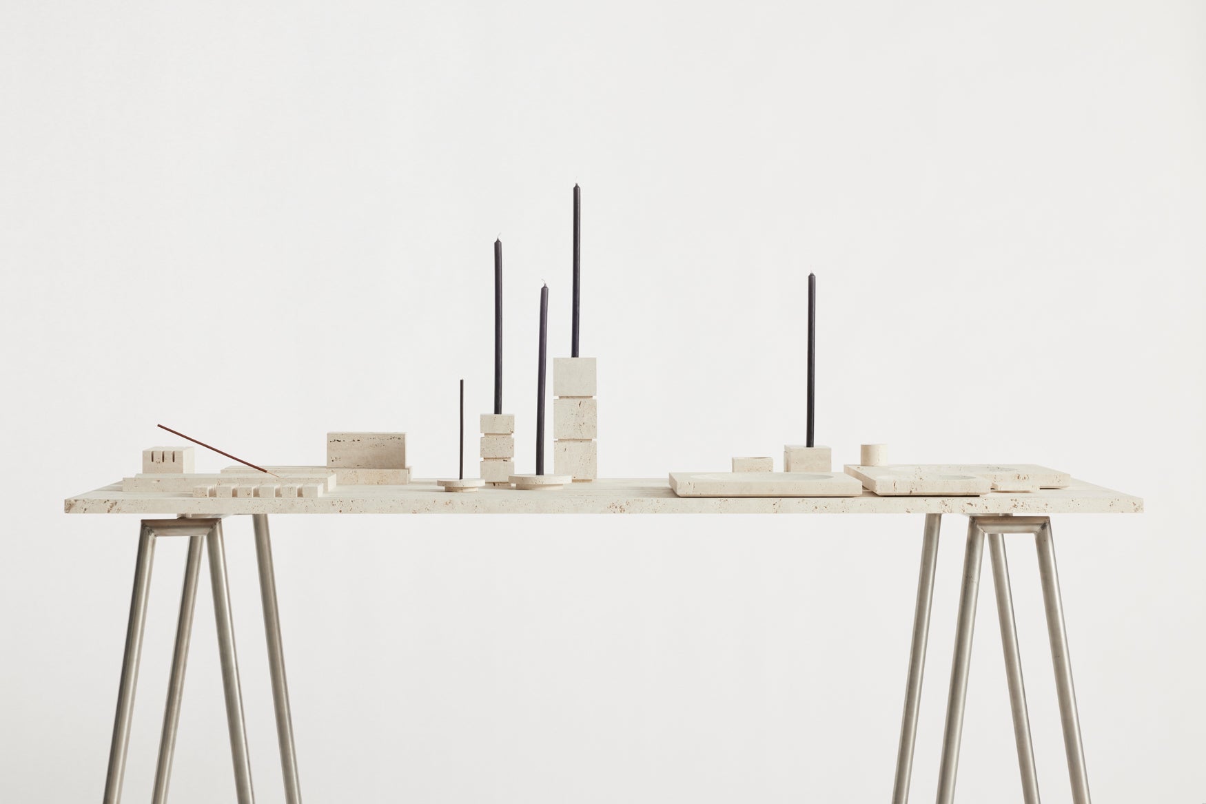 A table with a composition of various travertin sculptural objects on it in different shapes and sizes 