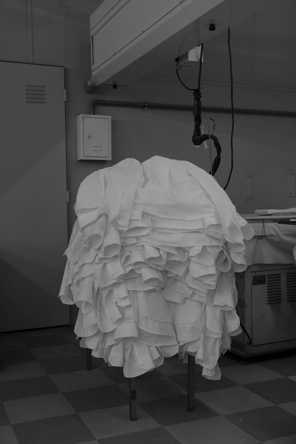 White shirts stacked on a table next to an ironing board. 