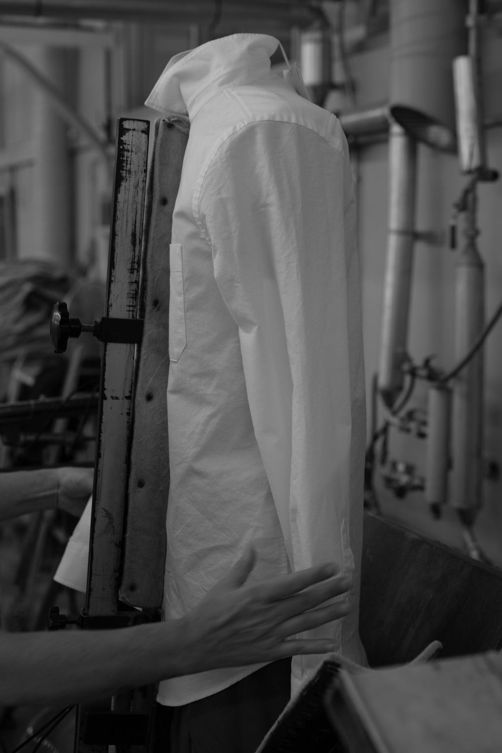 Hands holding a white shirt up straight on a steaming device