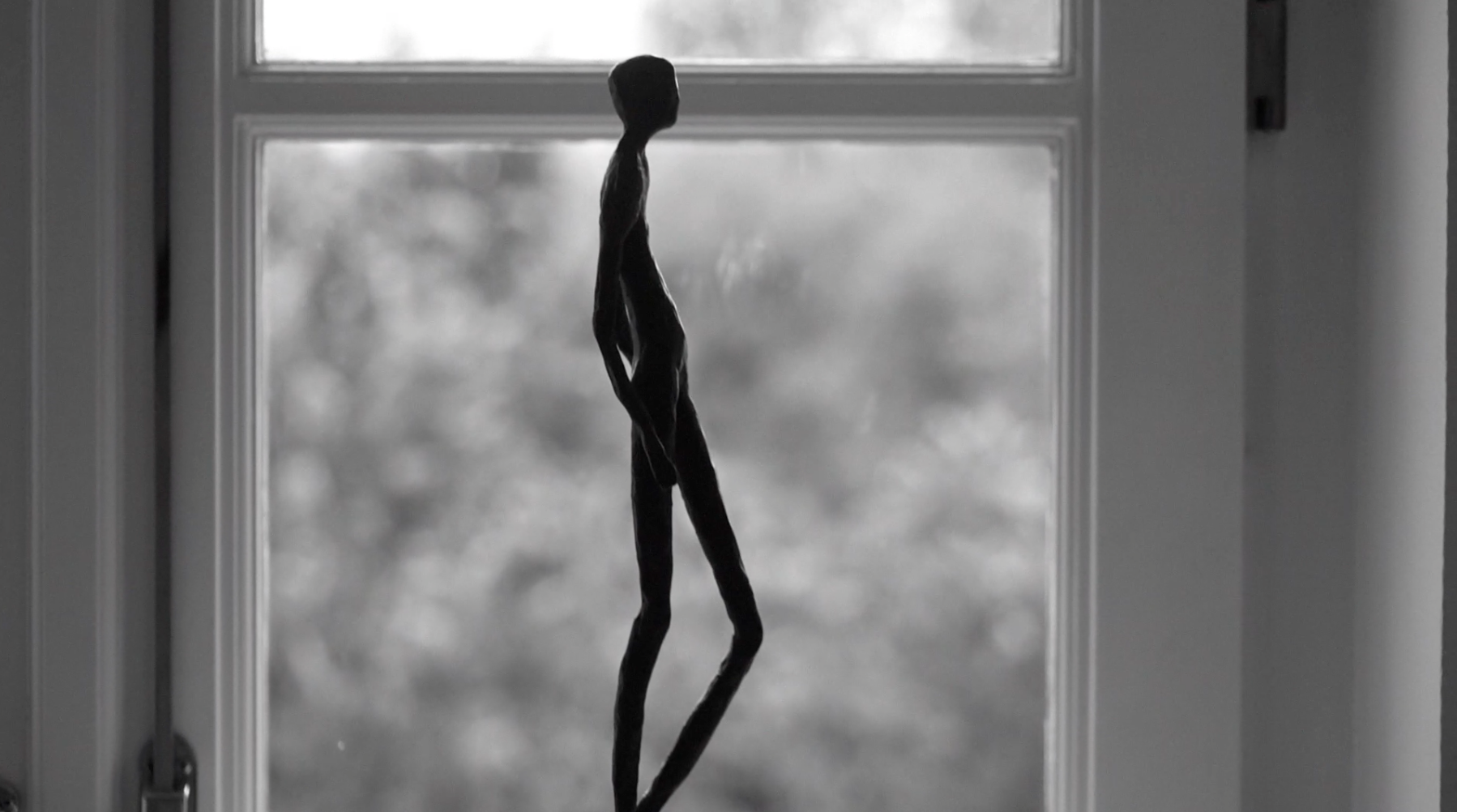 Bronze elegant figurine against a blurred window