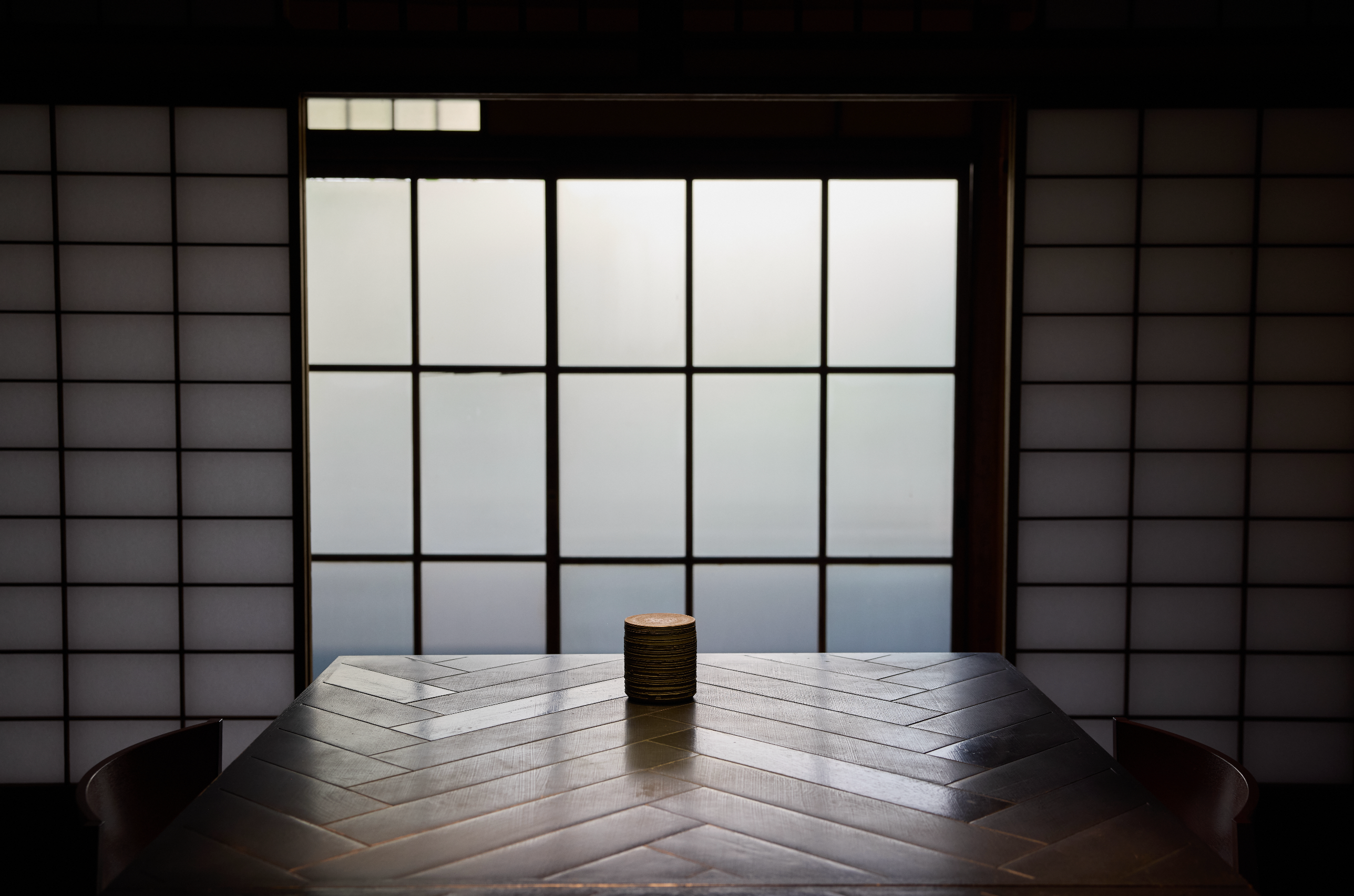 Ceramic pot on a wooden table in a Japanese interior with a large shoji doors and windows and diffused light