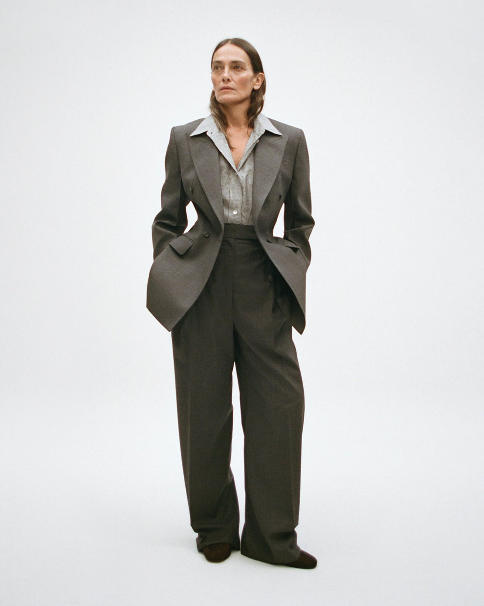 Woman wearing a gray hourglass shape blazer with matching trousers on a white background